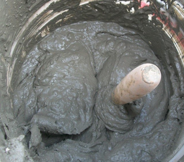 Mortier gris dans un seau avec un outil de mélange.
